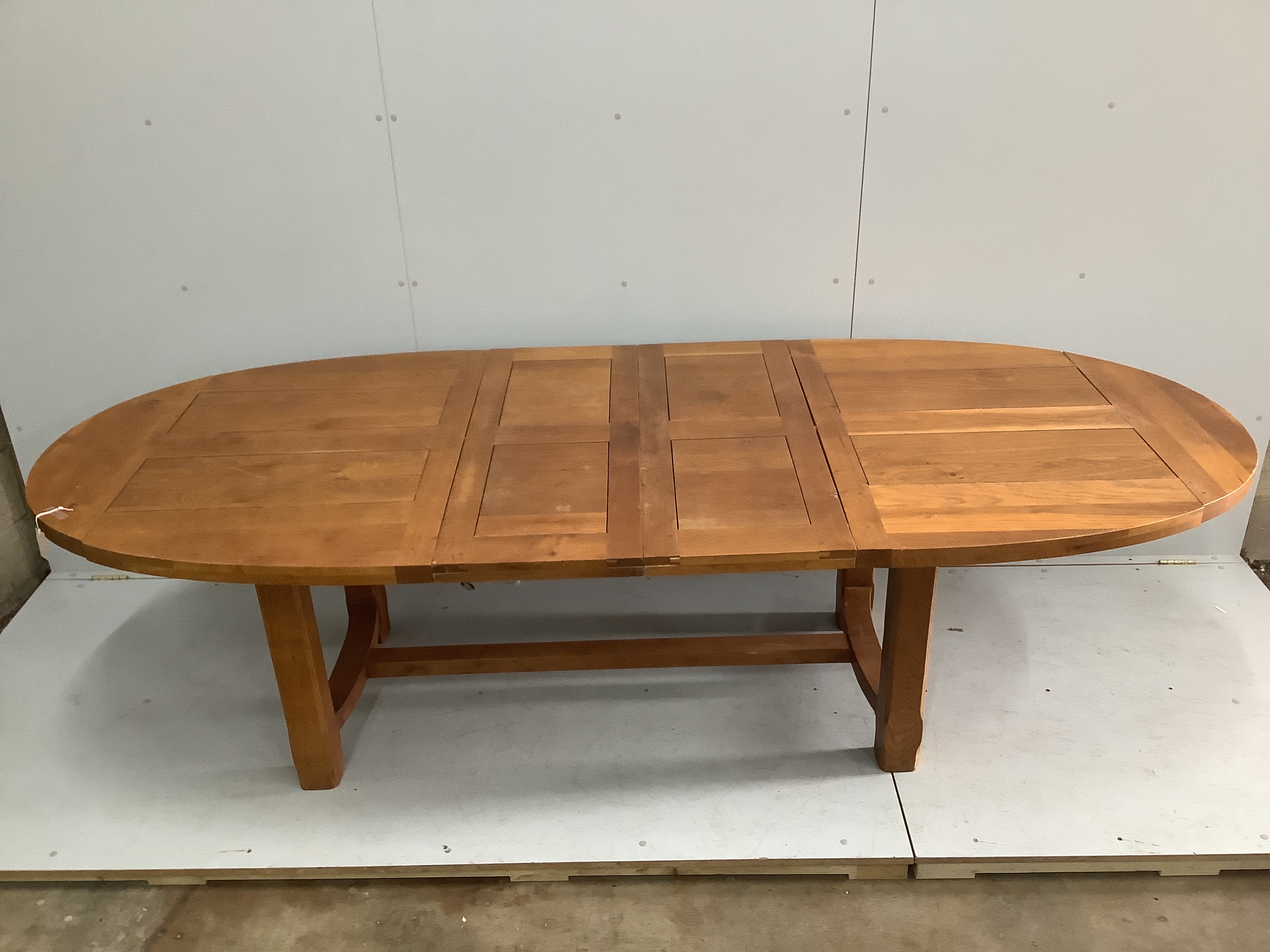 A contemporary oval oak extending dining table in the style of Pierre Chapo, 270cm extended, two spare leaves, depth 110cm, height 75cm